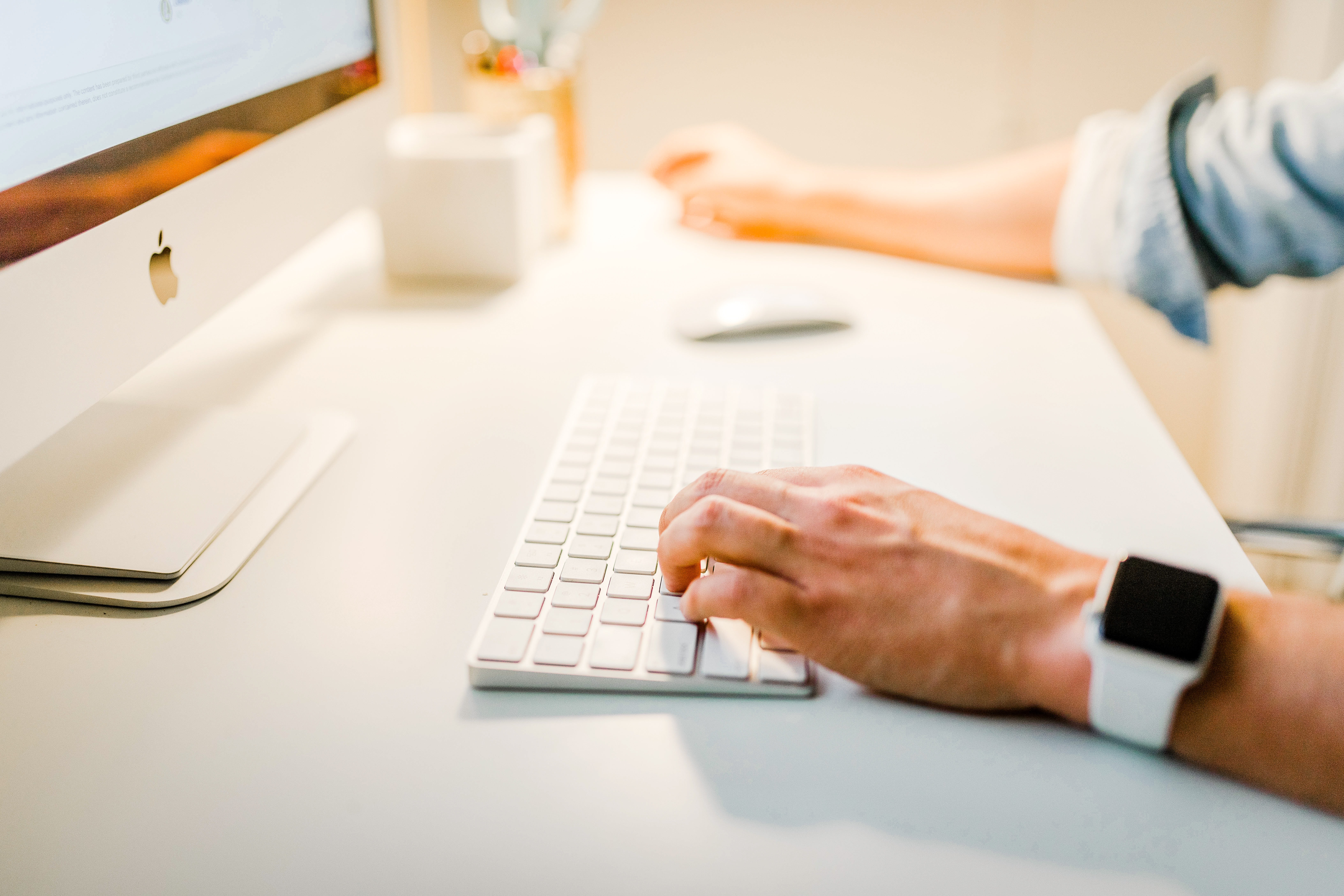 person using white keyboard in front of computer screen