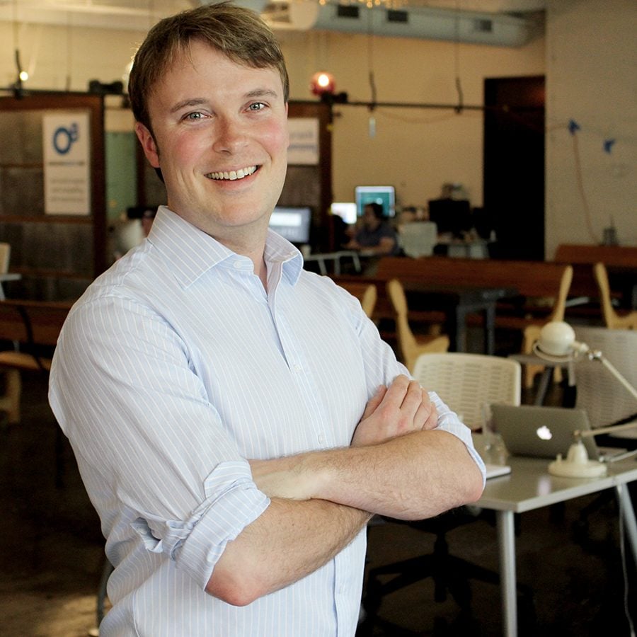 Seth Viebrock, CEO of O8, standing in the O8 office with the team working behind him