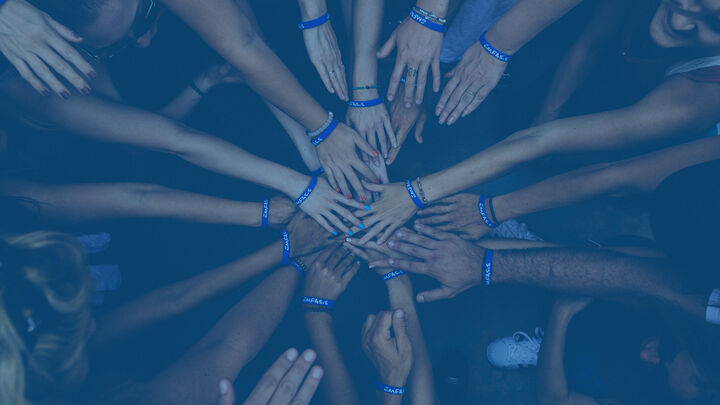 Marketing team members joining hands together in a collaborative huddle, symbolizing teamwork and unity
