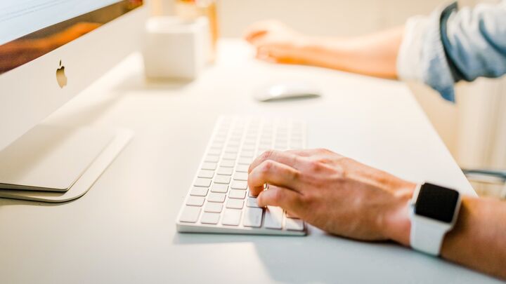 Man's arms typing at a computer