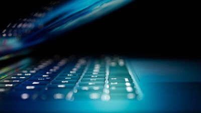 Image of a partially closed laptop illuminating the keyboard
