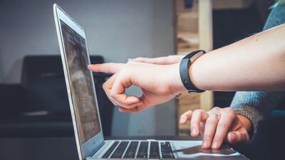 two hands pointing at a laptop