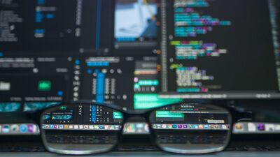 Glasses in front of a screen with lines of code on it