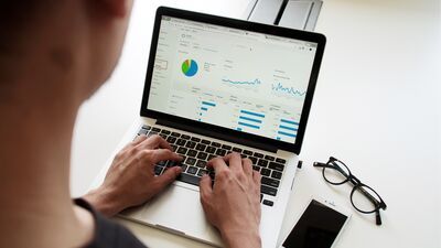 man standing over a laptop with graphs and charts on the screen