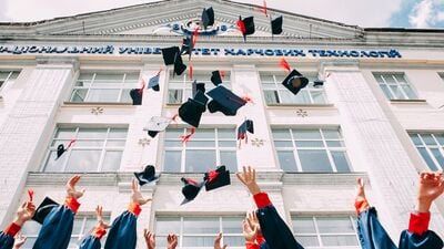 Image of students in caps and gowns throwing their caps into the air