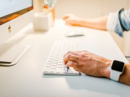 Man's arms typing at a computer