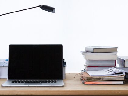 Laptop on a table next to a stack of books