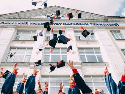 Image of students in caps and gowns throwing their caps into the air