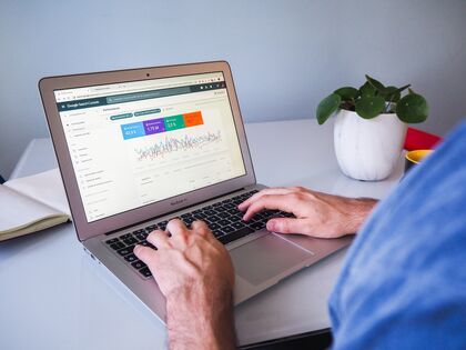 Person using Macbook Air on a white table