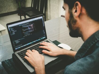 man typing code on laptop