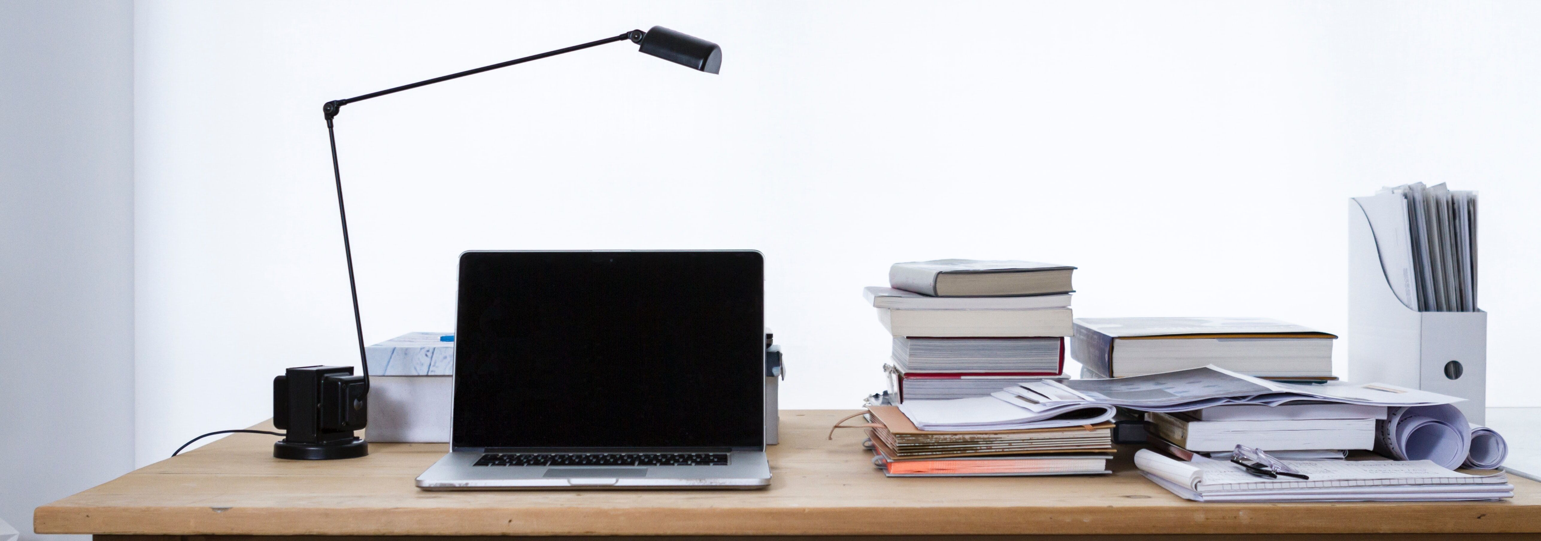 Laptop on a table next to a stack of books