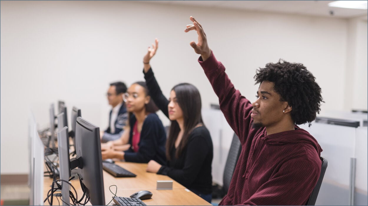 University students raising hands in class. 