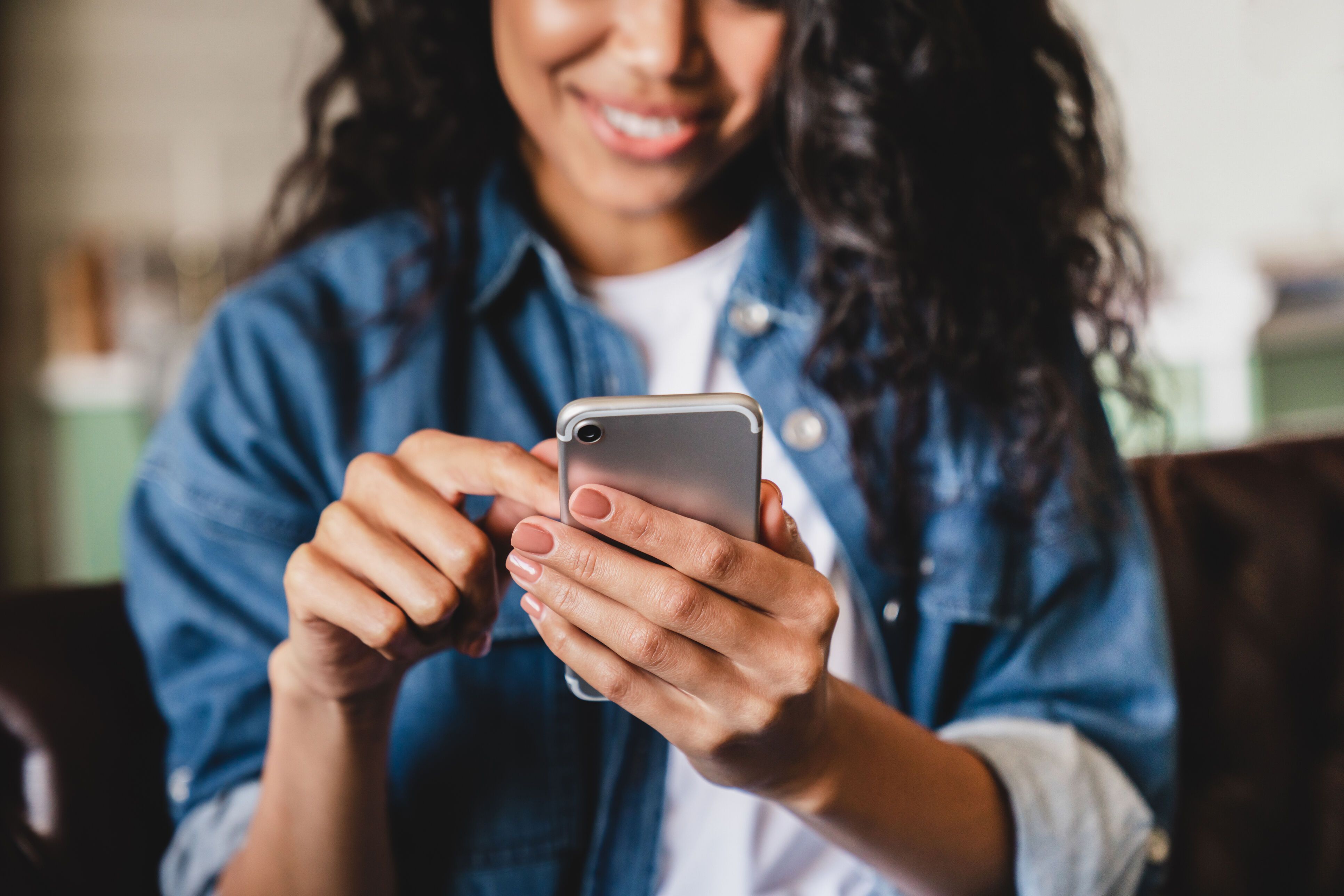 Cropped shot of a young woman using smart phone at home