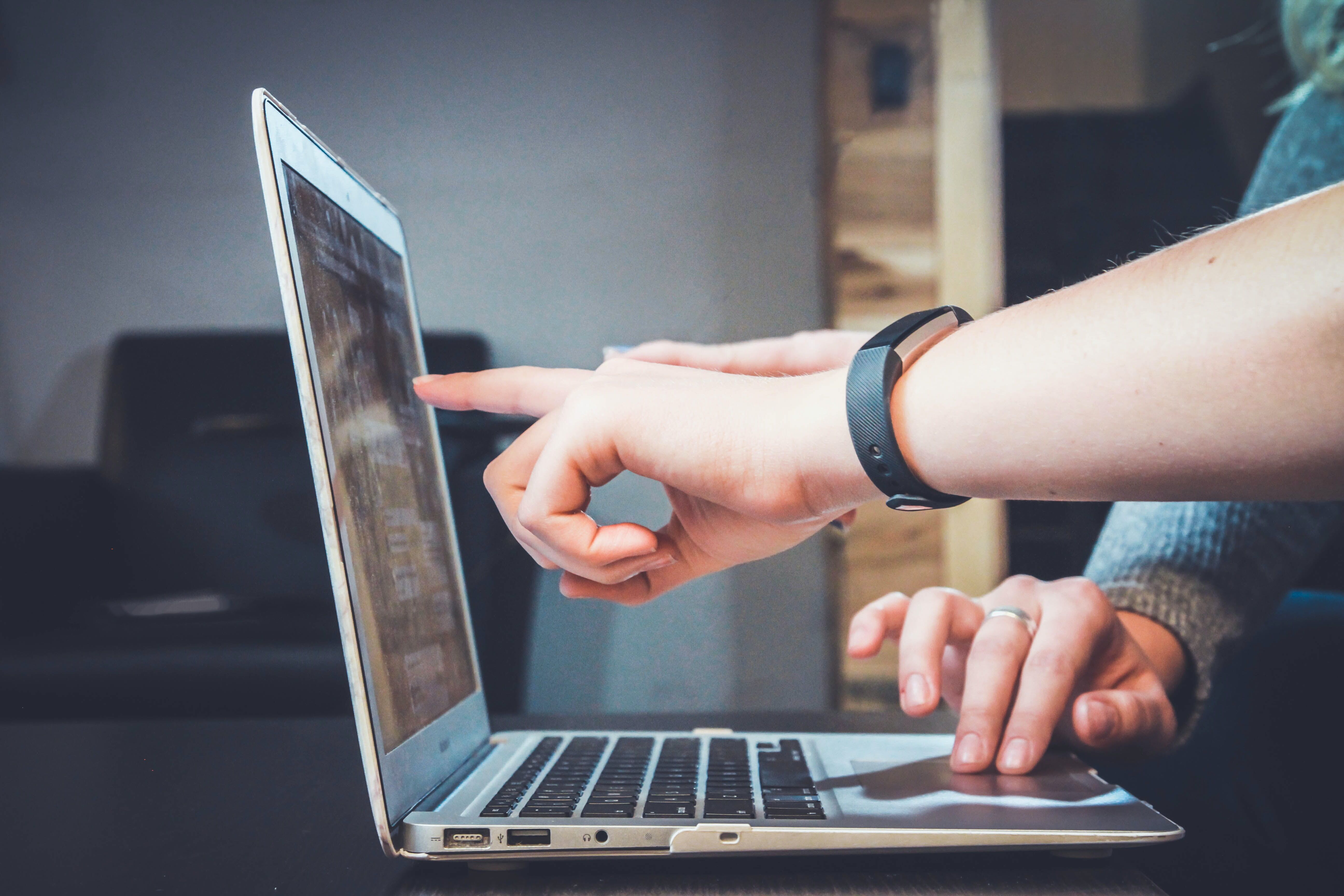 Two hands pointing at an open laptop screen