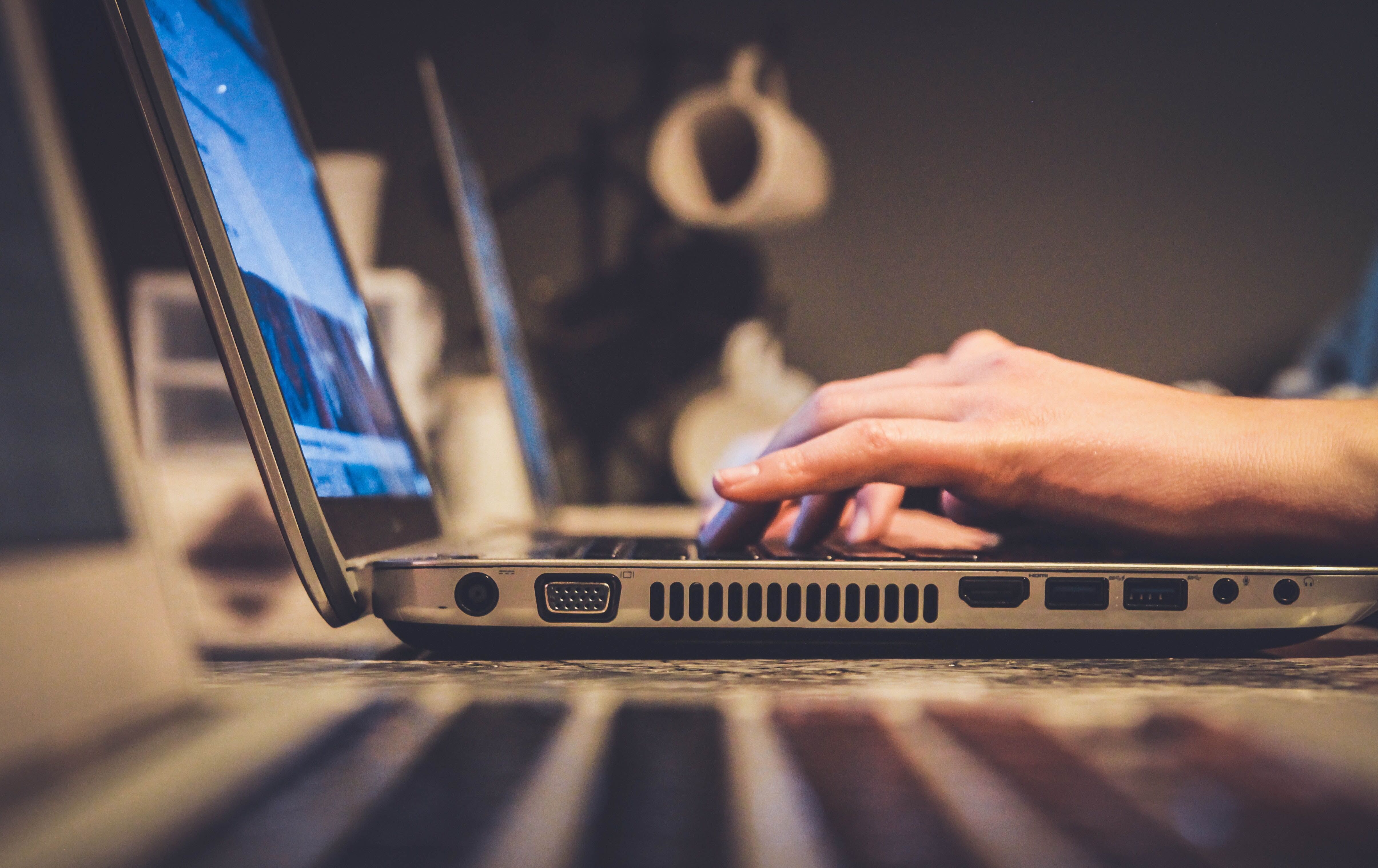 side profile of a laptop with hands typing on it