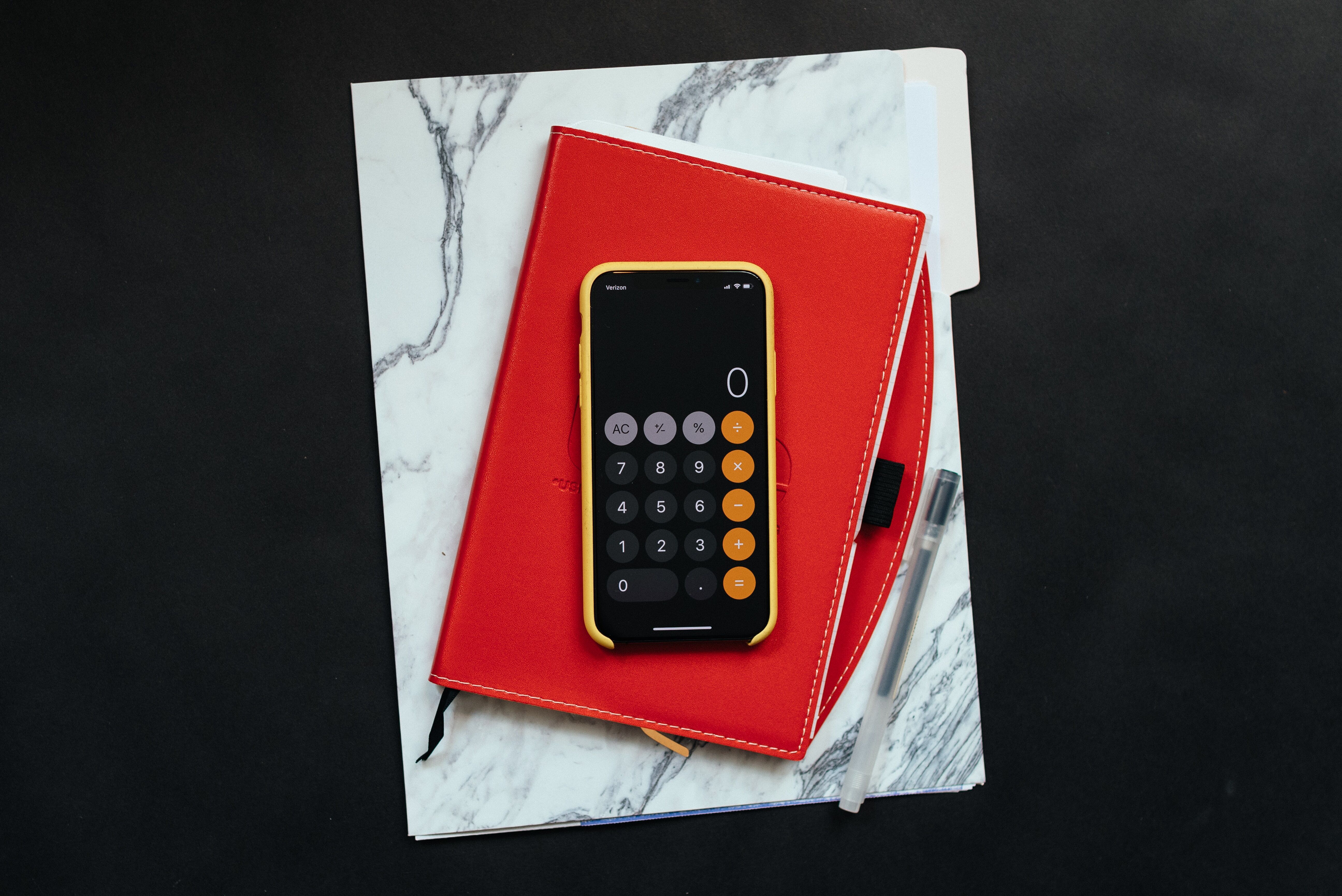 black phone sitting on top of a red planner notebook