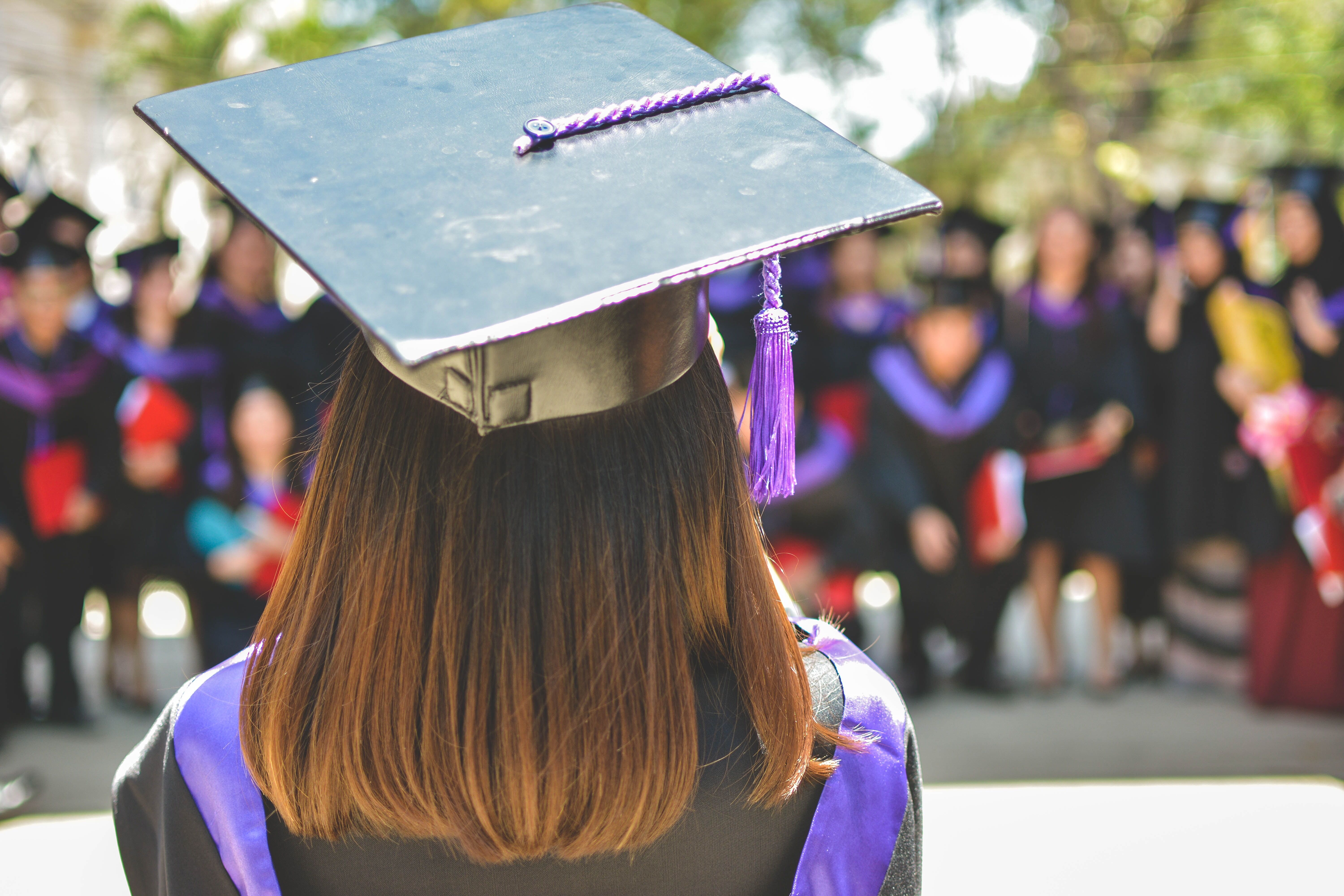 Image of the back of a student in a cap and gown, facing away from the camera