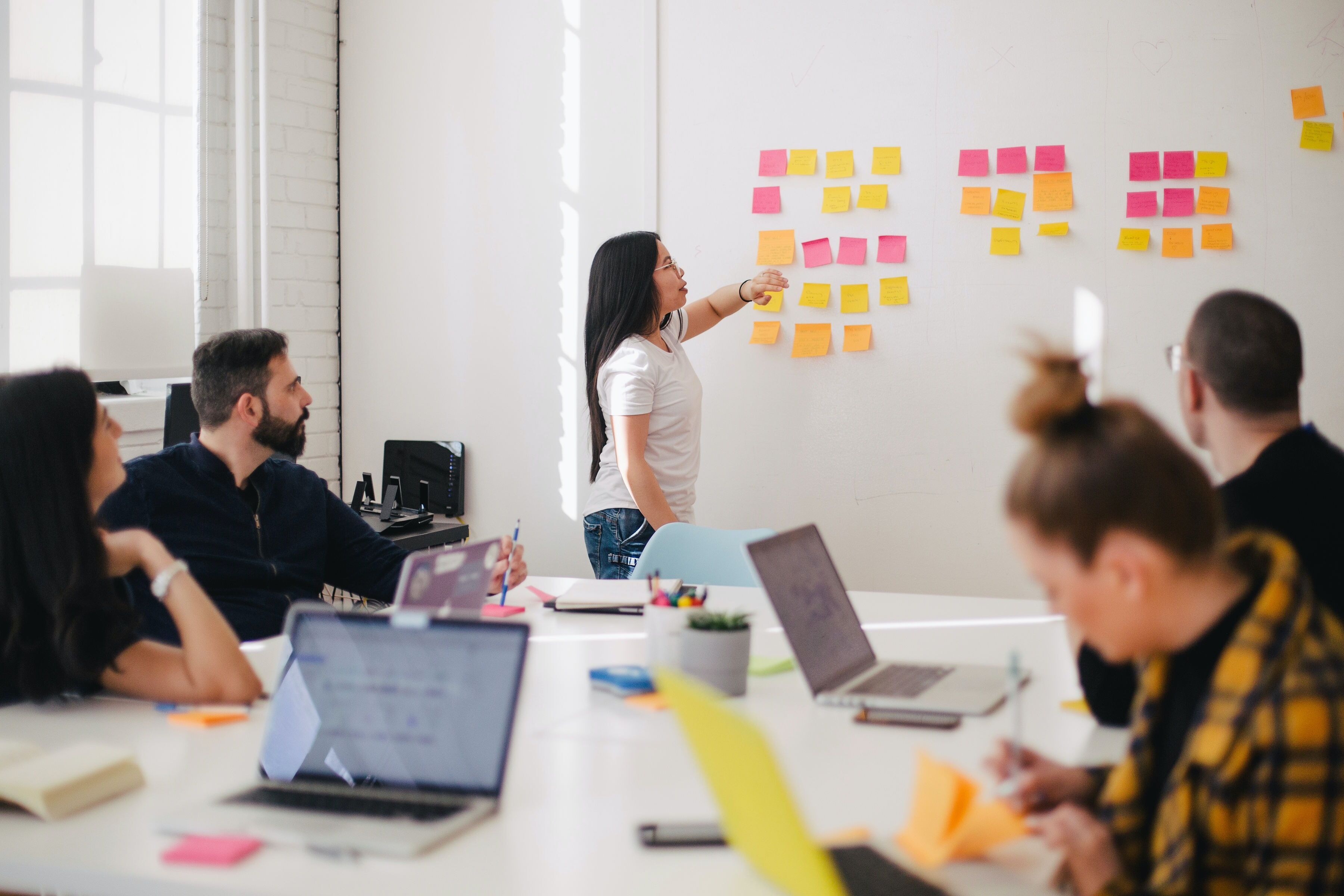 woman placing sticky notes on a whiteboard