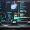 Glasses in front of a screen with lines of code on it